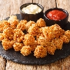 Chicken Popcorn are small slices of chicken that were coated breading and deep fried closeup in the slate dish on the table. Horizontal
